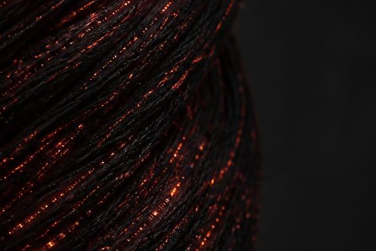 Macro photograph of black ReflexWear® yarn with fine red mineral particles inside the fibres